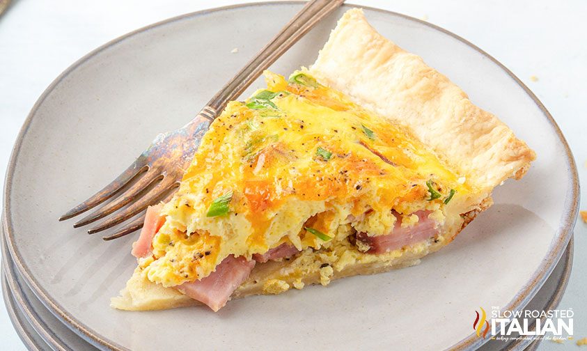 slice of quiche with ham and cheese on plate with fork