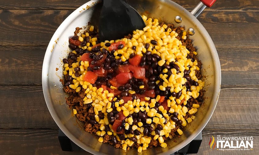 stirring corn and diced tomatoes into skillet with ground beef