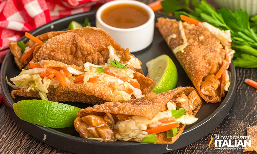 4 applebee's wonton chicken tacos on a plate with lime wedges and sauce