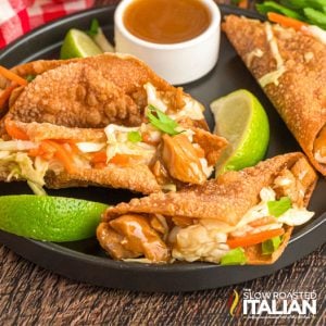 plate of wonton chicken tacos with lime wedges and dipping sauce