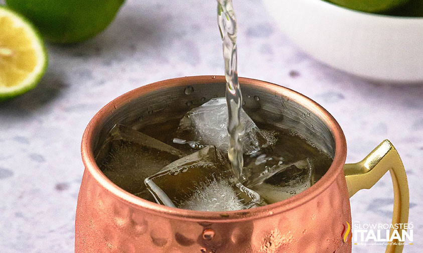 adding ginger beer to copper mug for kentucky mule recipe