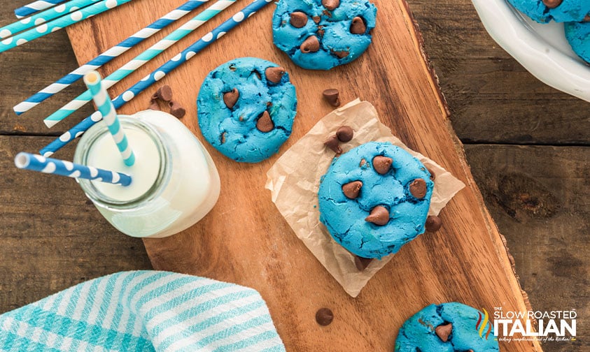 blue chocolate chip cookies with a glass of milk on a wood board