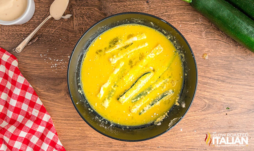 dipping zucchini sticks in beaten egg