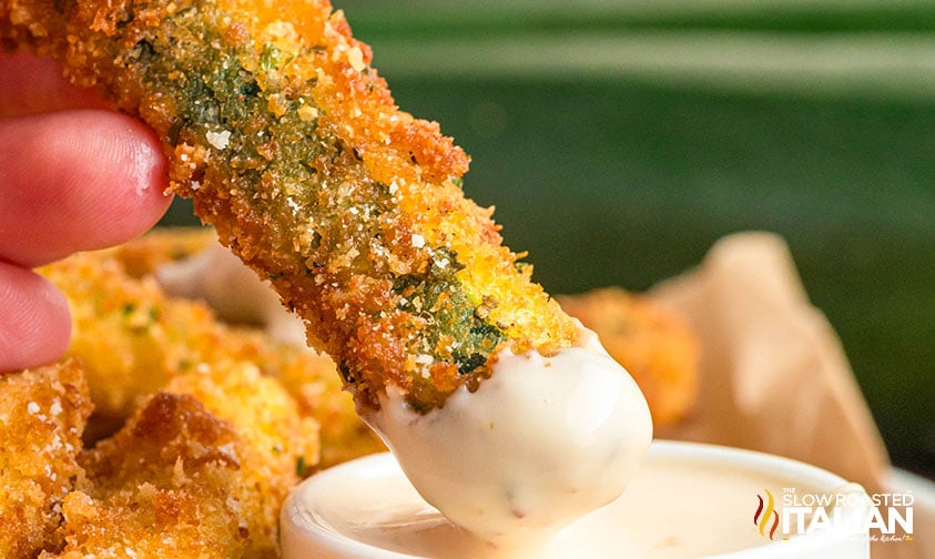 fried zucchini stick dipped in sauce