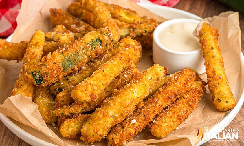 closeup plate of fried zucchini sticks with dipping sauce