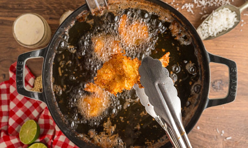 frying butterfly coconut shrimp in a large pot of oil