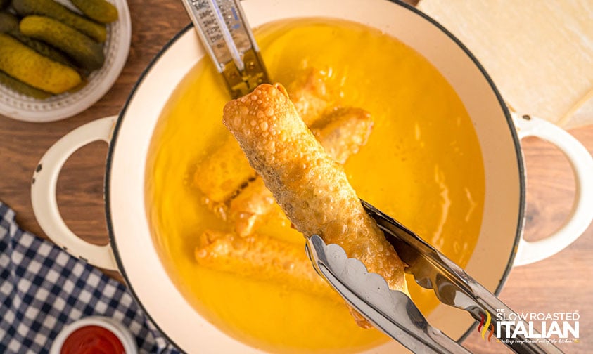 frying cheeseburger spring rolls in a large skillet