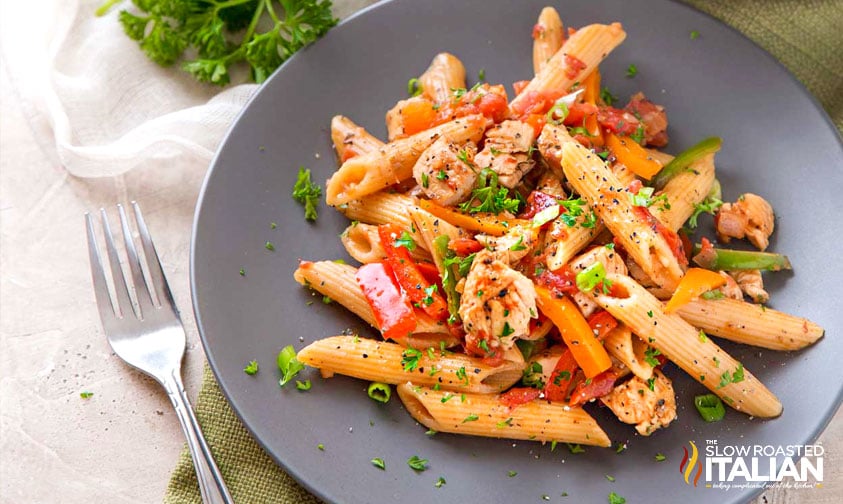 chicken fajita pasta on a grey plate with a fork