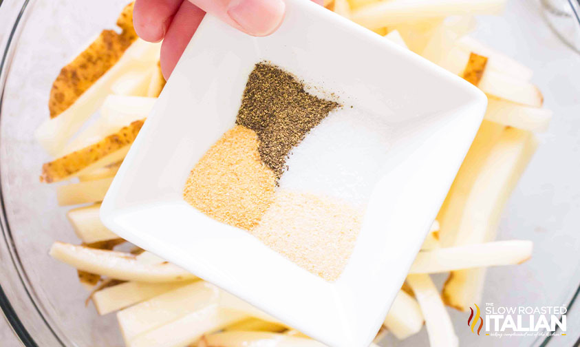 adding seasoning to cut french fries