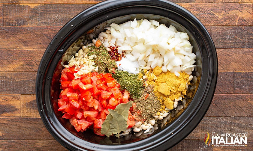 vegetables and seasonings added to beans in a crockpot