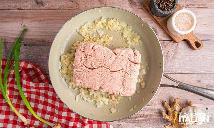 adding ground chicken to garlic and onion in a large skillet