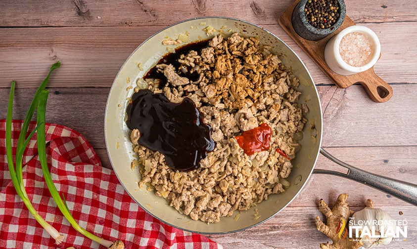 soy sauce, hoisin sauce sauce and sriracha added to ground chicken in a skillet