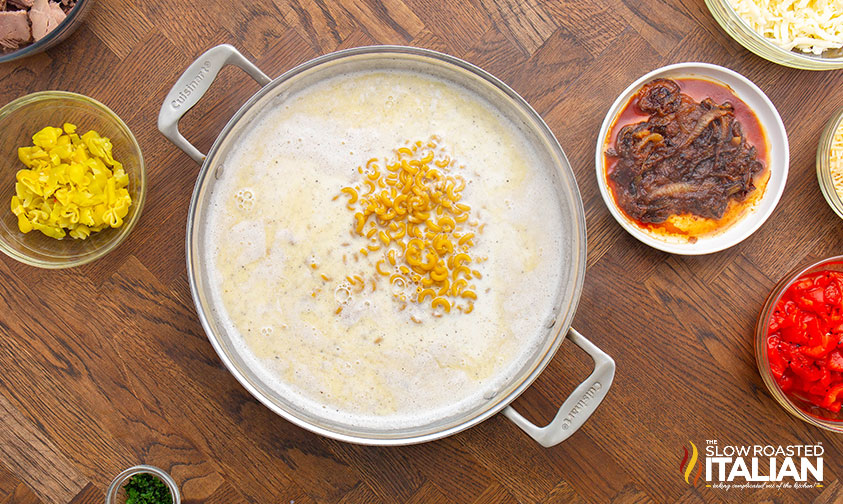 adding pasta to pot of milk, butter, salt and pepper