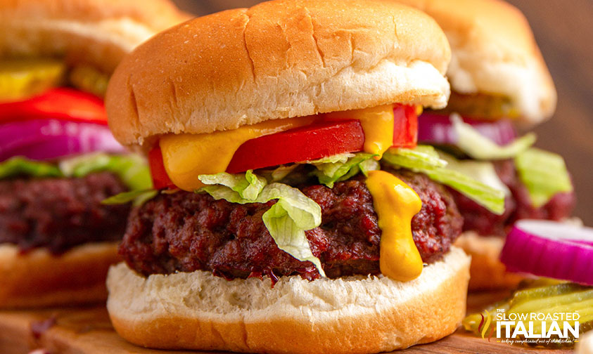 closeup of a smoked burger topped with lettuce, tomato and cheese