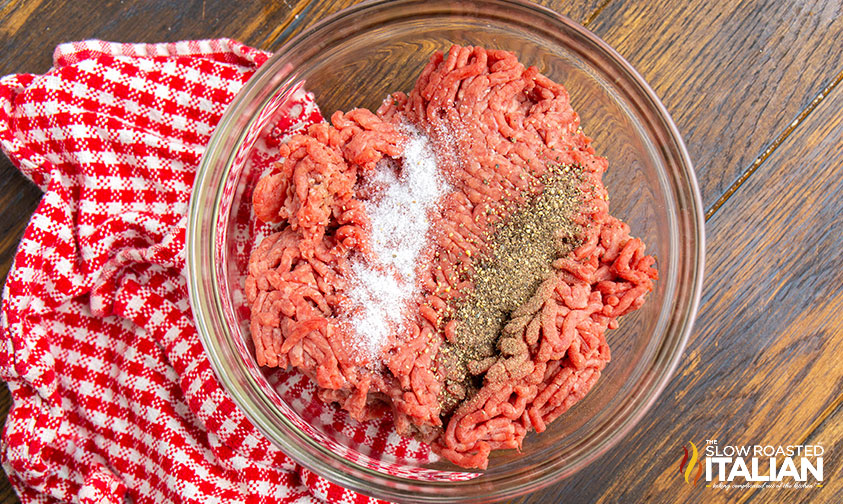 mixing ground beef, salt and pepper in a mixing bowl