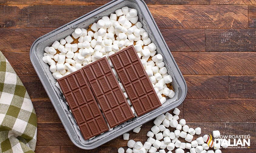 layering marshmallows and chocolate bars in baking pan