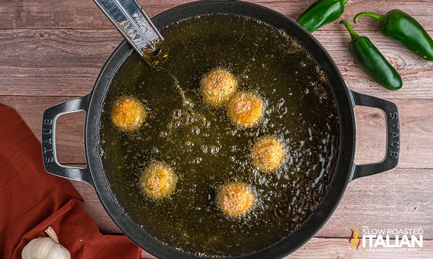 fried jalapeno popper cheese balls in a large pot of oil
