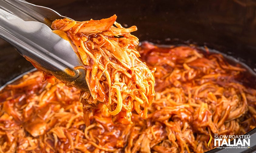 closeup of bbq shredded chicken in tongs