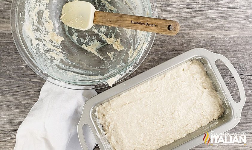 beer bread batter in loaf pan next to empty bowl with spatula