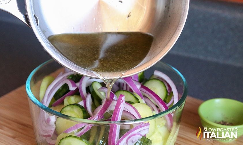 pouring vinegar dressing over cucumbers and onions