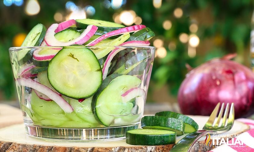 fork next to clear bowl of cucumbers and onions in vinegar dressing