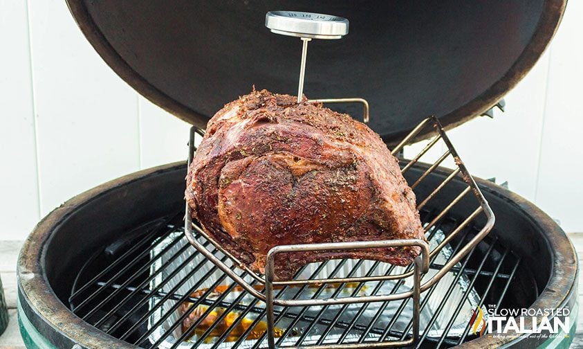thermometer stuck in prime rib roast sitting in roasting rack on grill