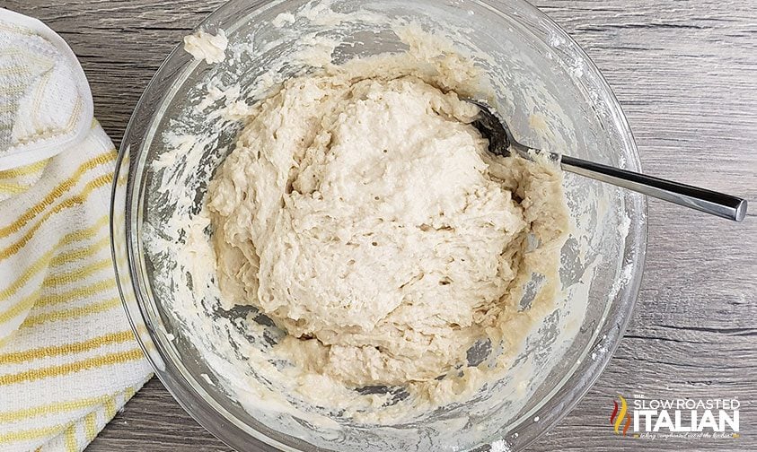 mixing beer bread dough in clear bowl with spoon