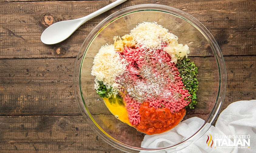 ground beef, seasoning, eggs, and cheese added to a large mixing bowl