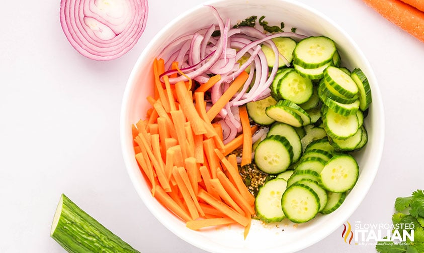 sliced cucumbers, carrots and onions in a large mixing bowl