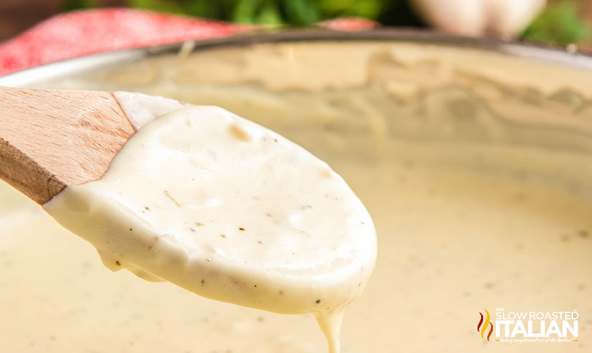 low carb alfredo sauce dripping from a wooden spoon