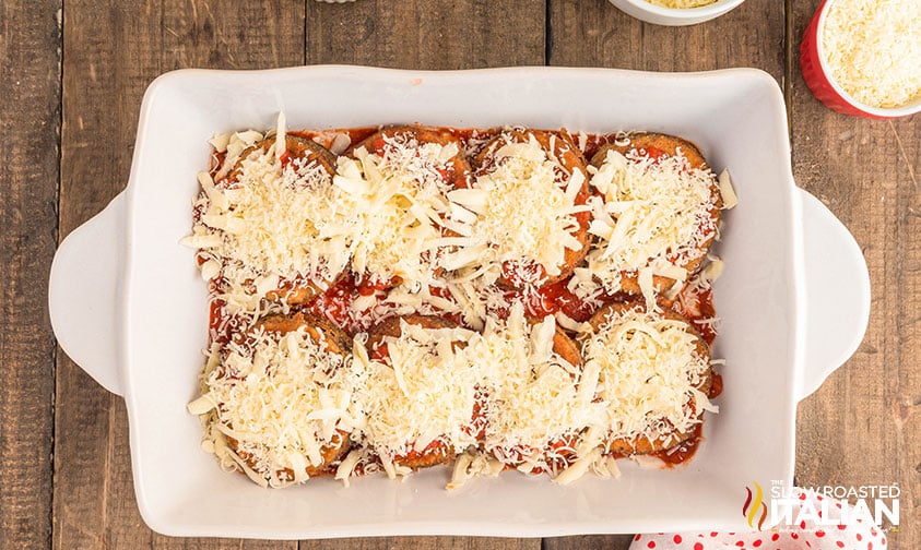 fried eggplant in baking dish covered in sauce and shredded cheese