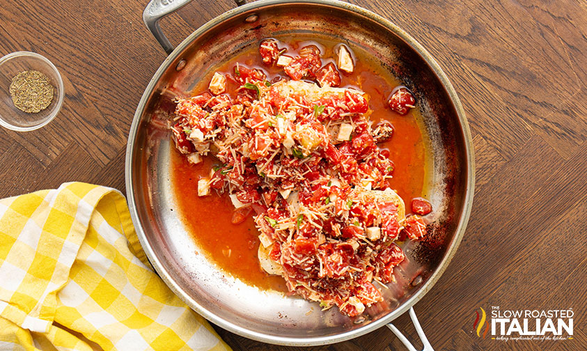 adding liquid and tomato cheese mixture to chicken breasts in a skillet