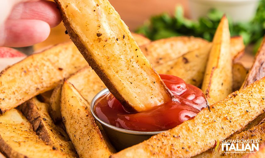close up: dipping homemade seasoned steak fries in ketchup