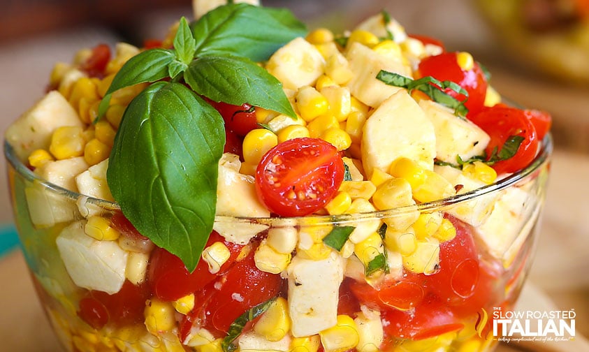 close up: summer corn salad topped with sprig of fresh basil