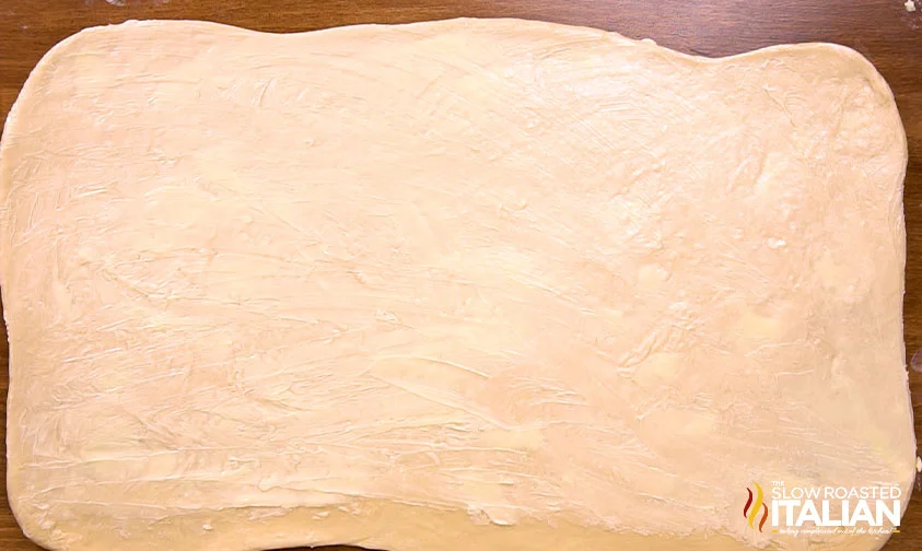 cinnamon roll dough shaped into a rectangle with butter spread on top