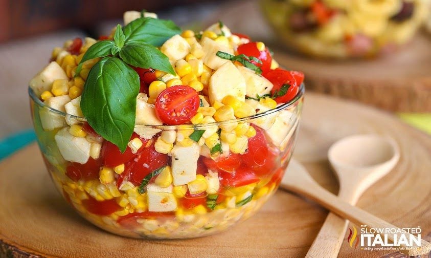 corn and tomato salad with basil and mozzarella in clear bowl