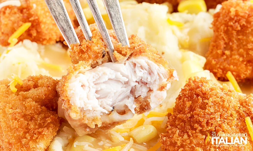 closeup: popcorn chicken sliced open on a fork in a KFC mashed potato bowl