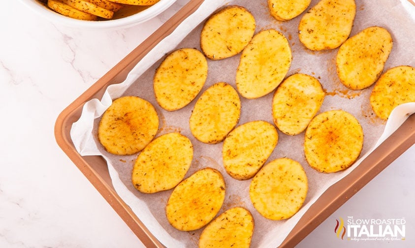 seasoned potato slices on a parchment-lined baking sheet