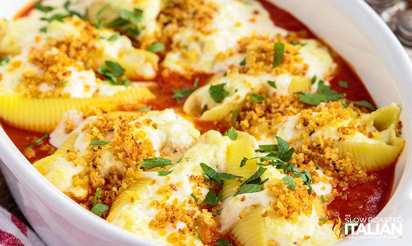 stuffed Italian shells with marinara and white sauce topped with toasted breadcrumbs and fresh parsley