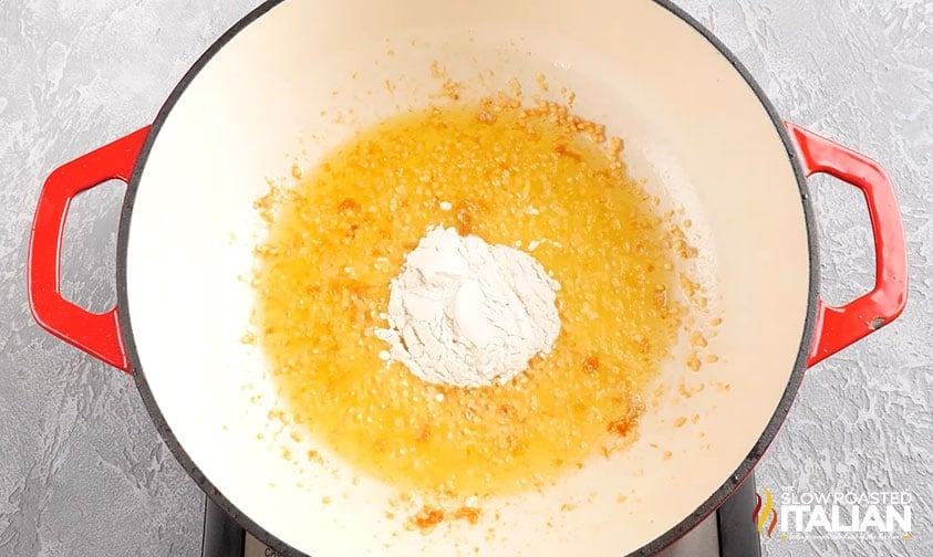 flour added to pot with butter and garlic to make a roux