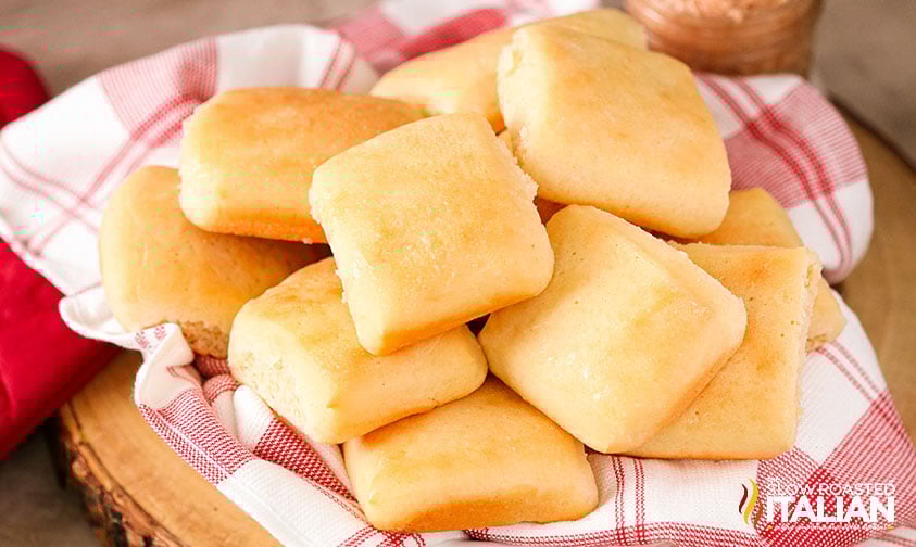 basket of homemade texas roadhouse rolls lined with red and white kitchen towel