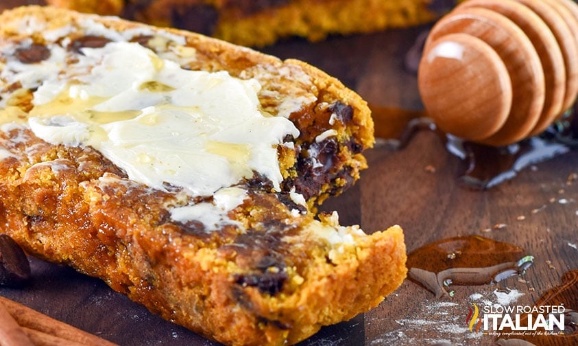 bite taken out of chocolate chip pumpkin bread topped with butter and honey