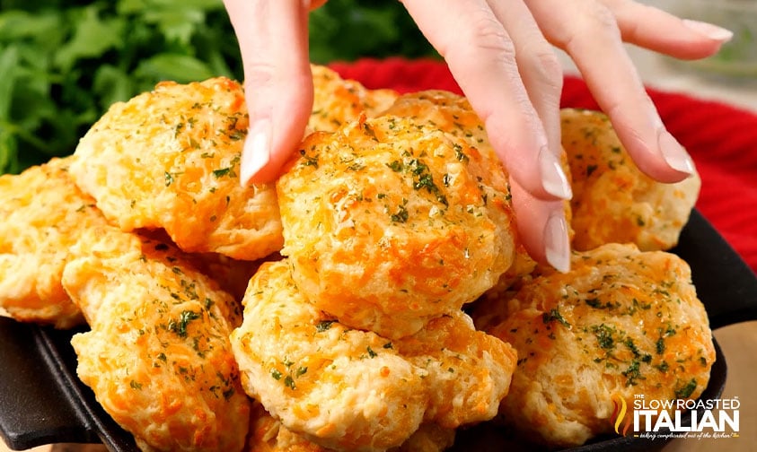 grabbing a cheddar bay biscuit off the top of a pile