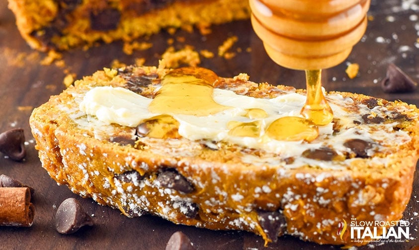 drizzling honey over slice of chocolate chip pumpkin bread smeared with butter