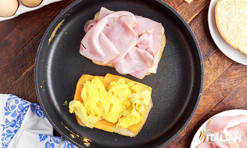 in skillet: bread slice with ham and bread slice with eggs and cheese