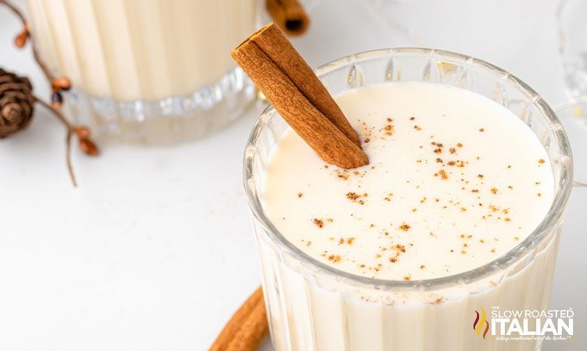 overhead: glass of puerto rican eggnog drink with nutmeg and a cinnamon stick