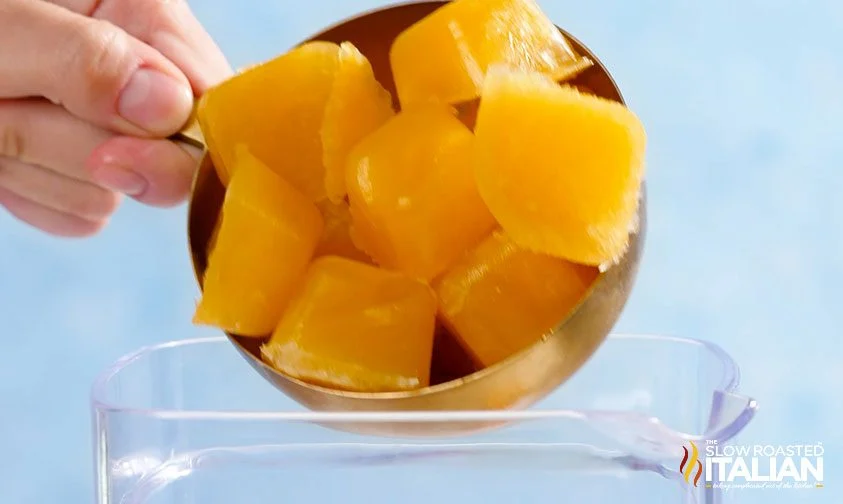 adding orange juice ice cubes to a blender
