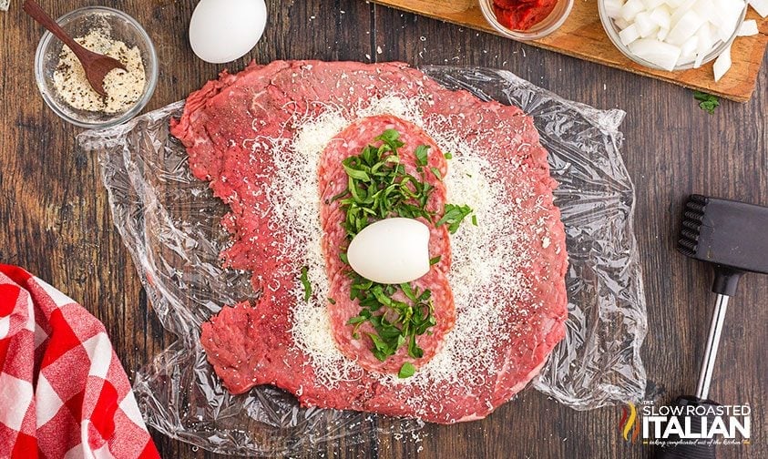 hard boiled egg, salami, herbs, and cheese on piece of steak pounded thin