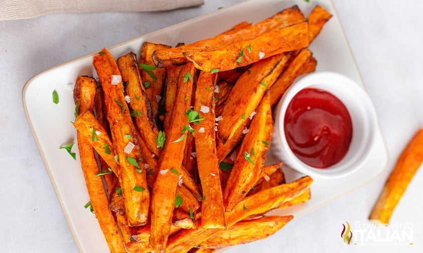 crispy air fryer sweet potatoes fries topped with parsley and flakey sea salt with ketchup