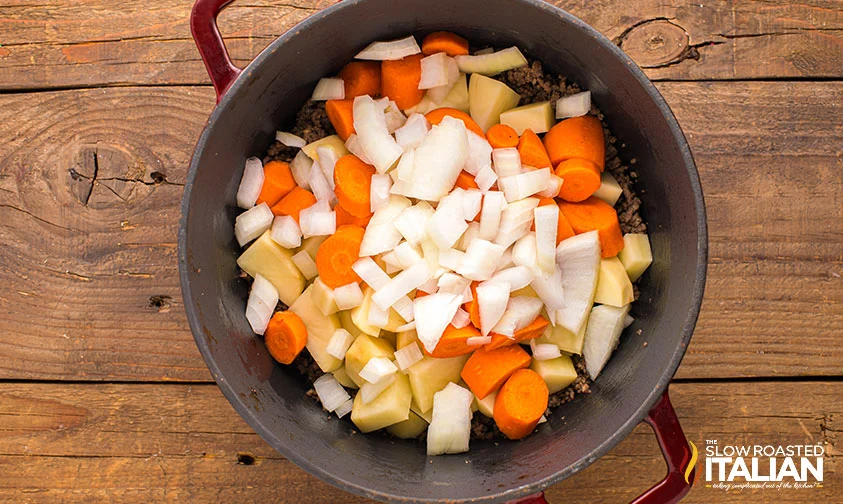 chopped potatoes, carrots, and onions in pot with browned ground beef